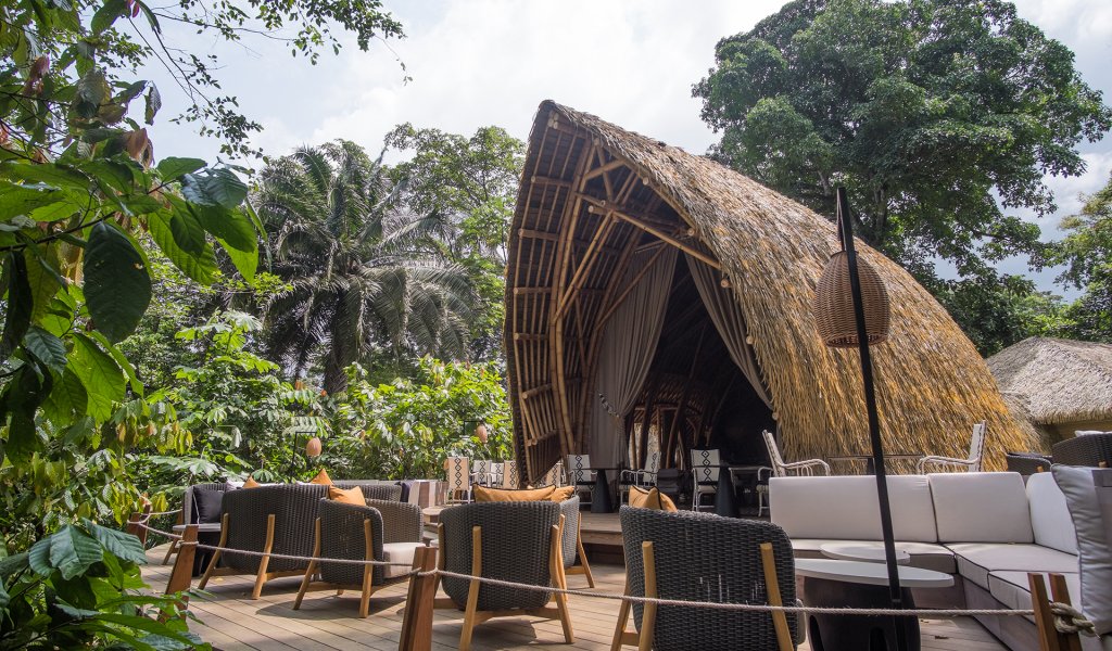 Outdoor seating area and bamboo structure of OKA Sundy restaurant surrounded by lush greenery
