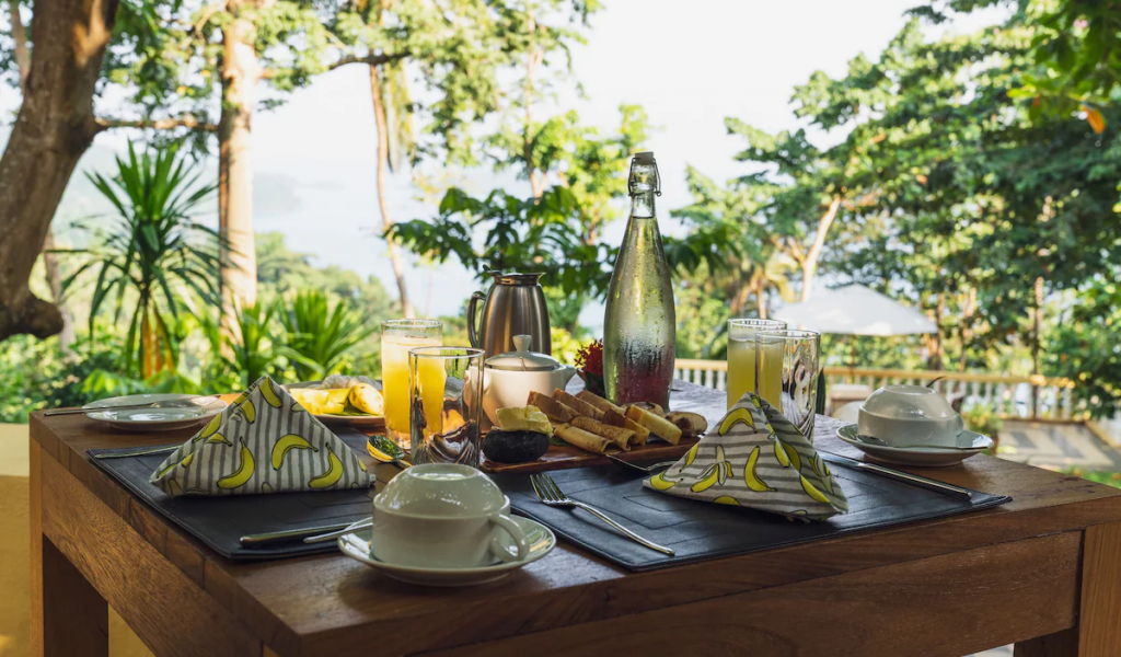 Breakfast table on the terrace at Belo Monte, fresh juices and pastries with ocean views of Príncipe Island.
