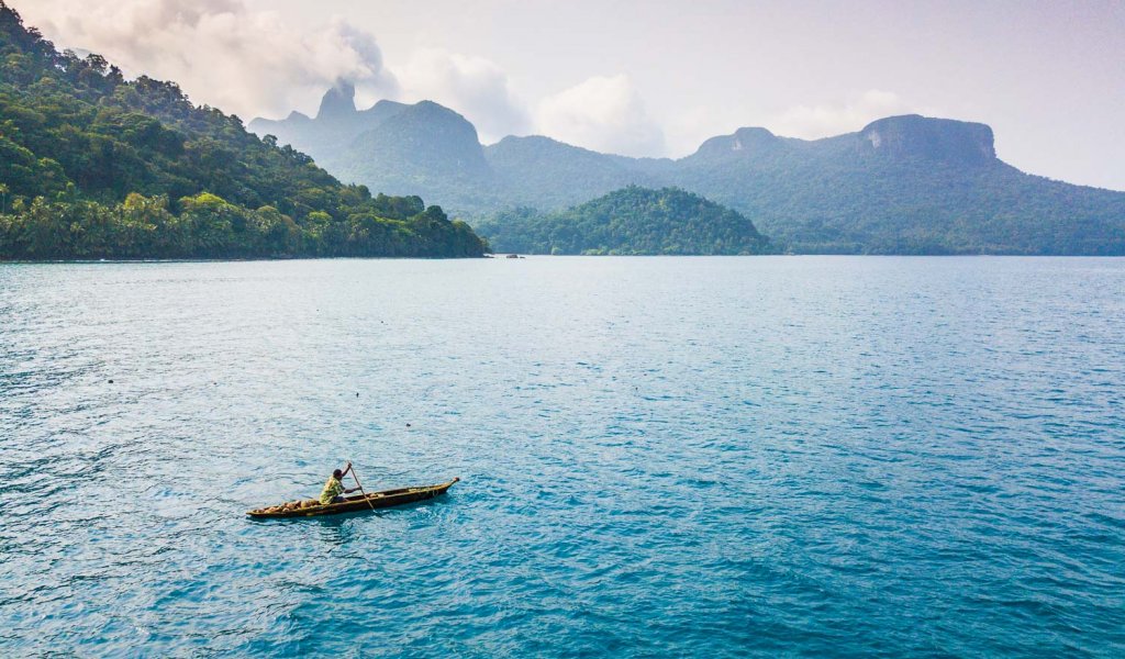 A person floating on a small wooden boat over the sea near São Tomé Island