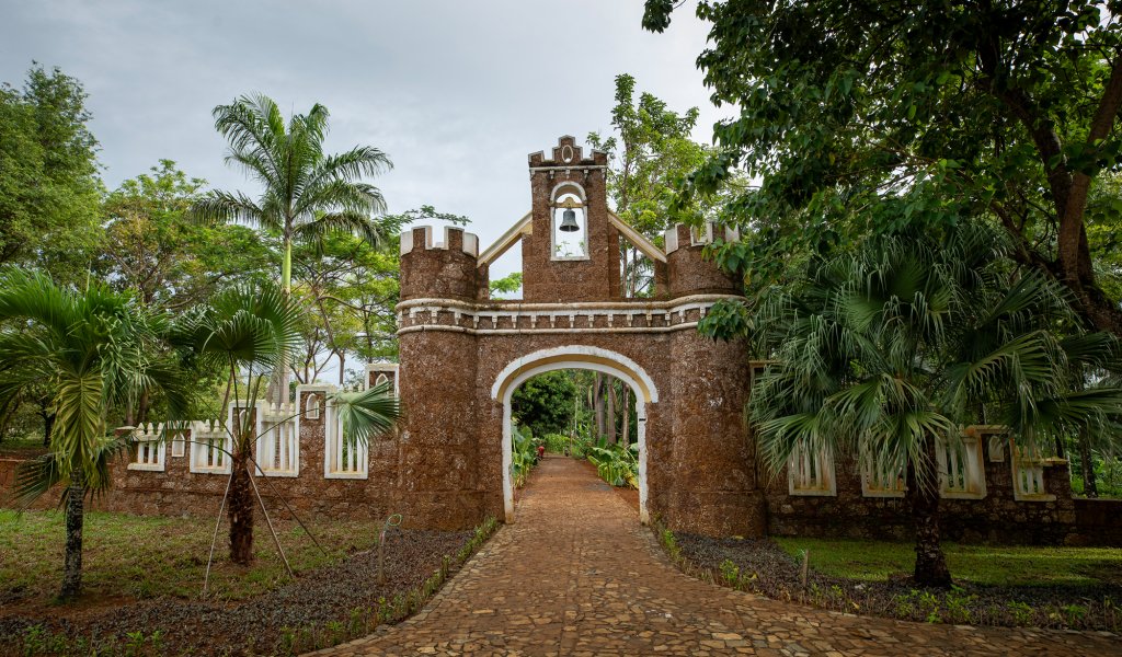 Fortified stone gateway and bell tower framed by palms and tropical gardens at Belo Monte