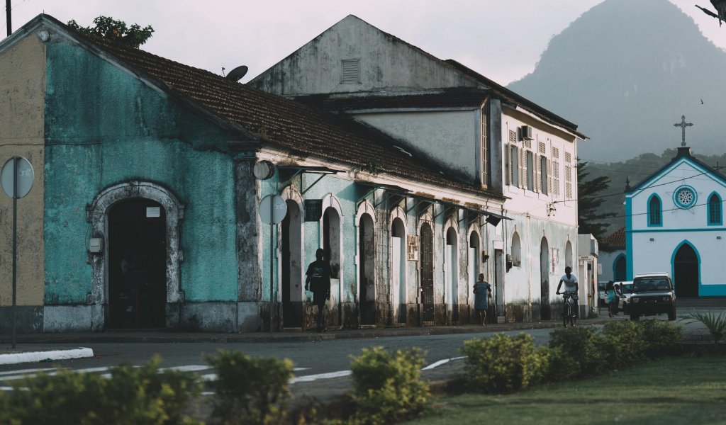Colourful colonial buildings and blue church with a rocky peak in the background in Santo António, Príncipe Island