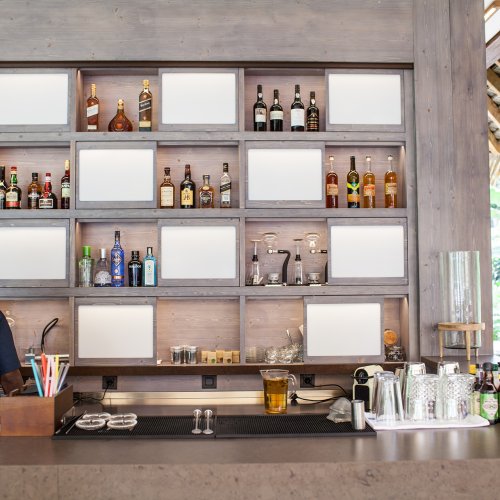 Um bar de bebidas com garrafas em prateleiras e um homem a trabalhar atrás do balcão at Sundy Praia