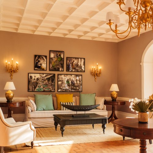 Sala de estar do Belo Monte com candelabro dourado, fotografias da ilha emolduradas e portas para o terraço