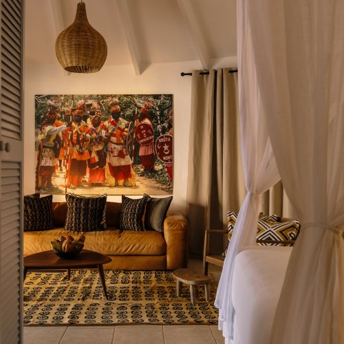 Living area with a couch and African art in a beach bungalow at Bom Bom Beach Resort.