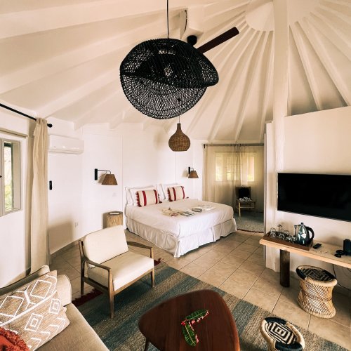 A vibrant bedroom with a bed, sofa, and TV lounge at Bom Bom Beach Resort.