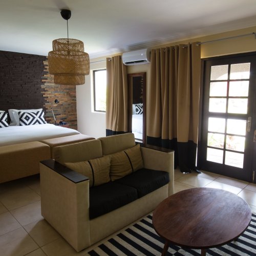Suite at Omali with bed, couch, striped rug, and wooden accent wall.