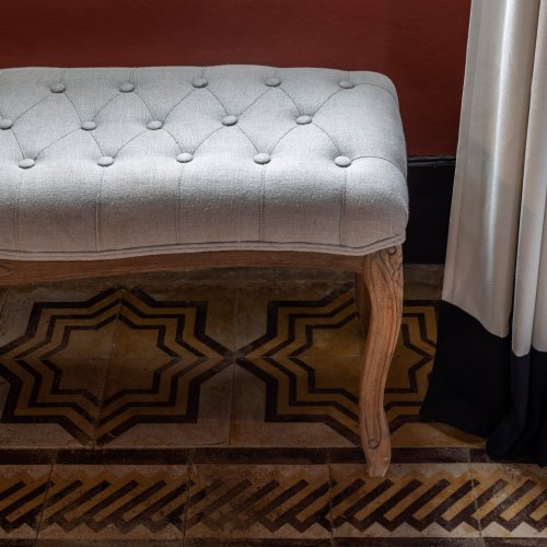 Close-up of a tufted bench and decorative patterned tiles at Roça Sundy