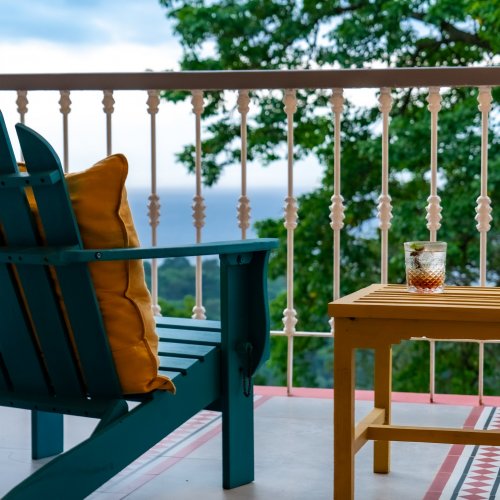 Glass of a refreshing drink on a balcony with ocean and forest views at Roça Sundy