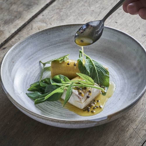 Prato de alta gastronomia apresentado numa mesa no restaurante OKA Sundy