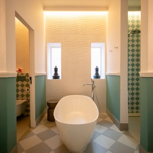 Belo Monte bathroom with a freestanding bathtub, walk-in shower and chequered tiled floor