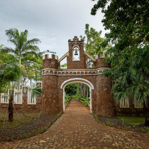 Fortified stone gateway and bell tower framed by palms and tropical gardens at Belo Monte