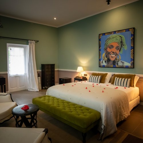 Belo Monte room with green walls, a framed portrait and an armchair seating area beside the bed