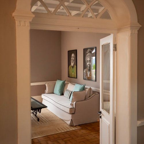 View through an arched doorway into the Belo Monte lounge with a cream sofa and framed portraits