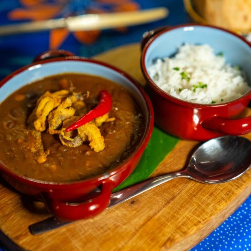 Guisado tradicional são-tomense com arroz e malagueta servido numa tábua de madeira no restaurante do Omali, Ilha de São Tomé