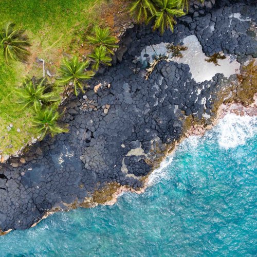 Vista aérea das rochas vulcânicas escuras junto ao oceano turquesa na Boca do Inferno, Ilha de São Tomé