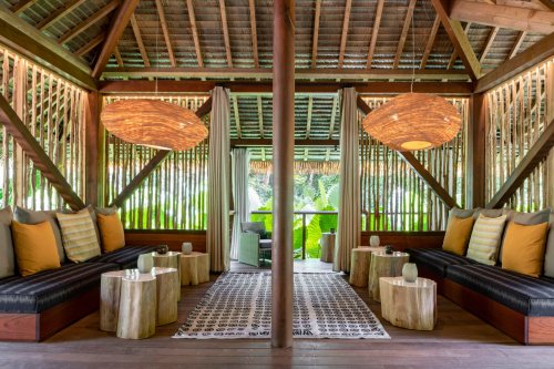 Covered terrace with seating, small wooden tables, and large hanging lamps at Sundy Praia