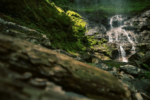 Cachoeira flui sobre as rochas da Ilha do Príncipe, parcialmente coberta de musgo verde.