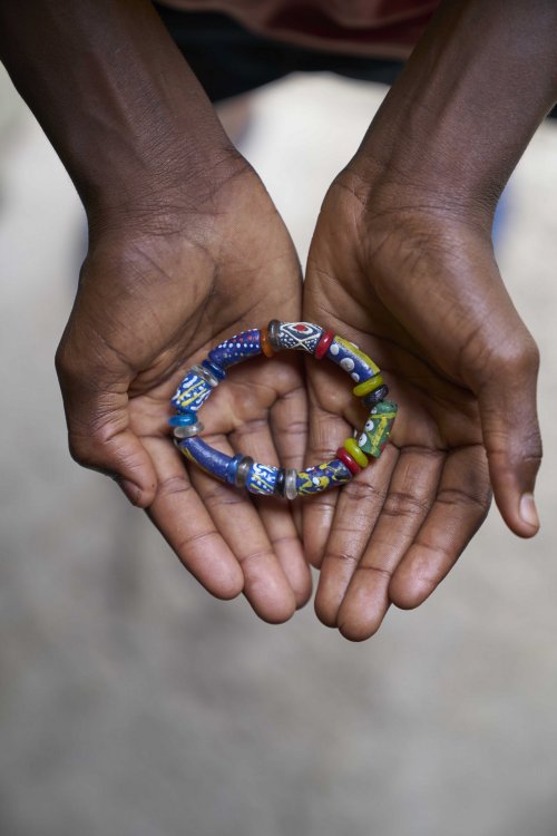 Mãos de artesã local segurando uma peça de joalharia artesanal na Ilha do Príncipe.