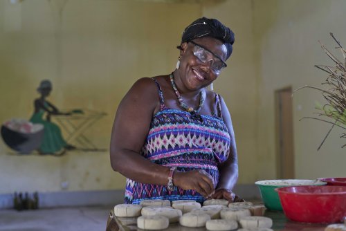 Local worker in a colourful dress and safety goggles smiles at us while working.
