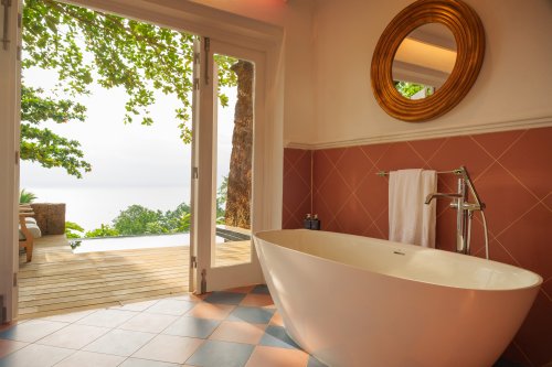Casa de banho do Belo Monte com banheira autónoma e portas para o deck com vista para o oceano
