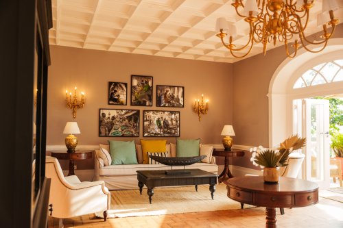 Belo Monte lounge with a gold chandelier, framed island photography and doors onto the terrace