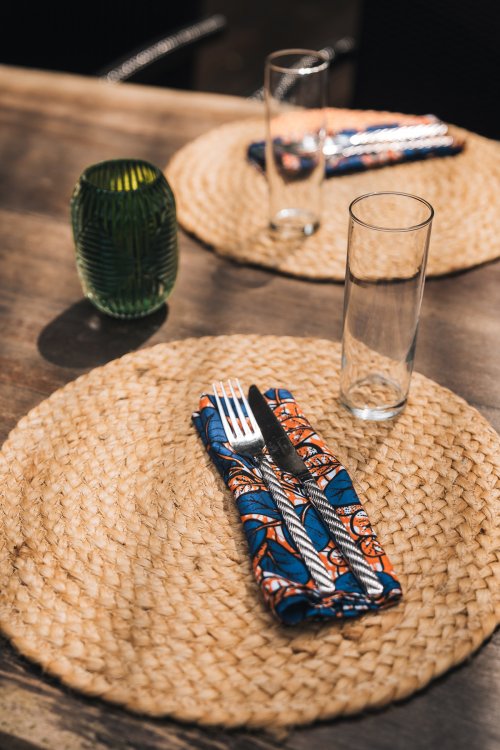 Talheres em guardanapo estampado sobre individual de palha no Bom Bom Beach Club