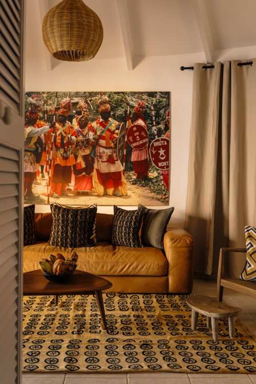 Área de estar com sofá e arte africana no bangalô de praia no Bom Bom Beach Resort.