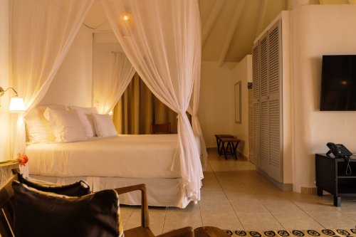 Bangalô de praia com cama com dossel no Bom Bom Beach Resort