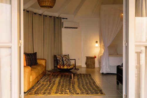  Living area with a couch and African art in a beach bungalow at Bom Bom Beach Resort.