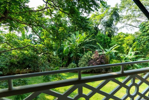View from a bedroom at Roça Sundy showing a balcony with lush greenery