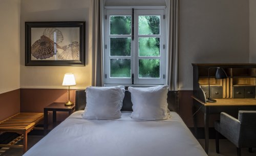 Quarto acolhedor na Roça Sundy com cama, secretária, vista para vegetação e luz suave