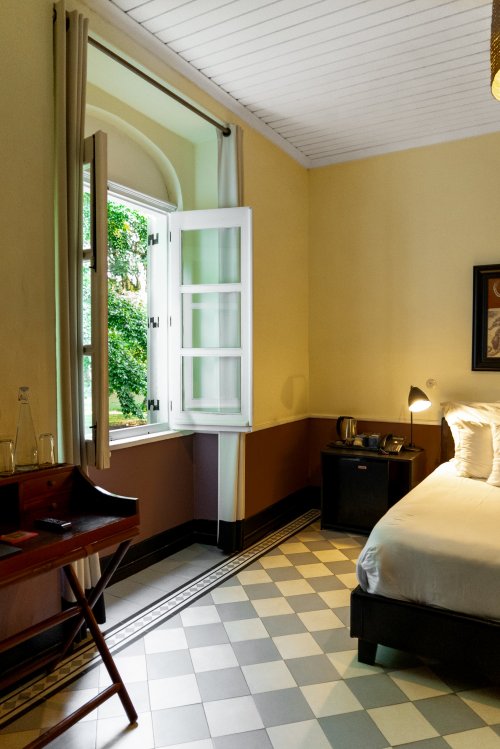 Bedroom at Roça Sundy with an open window, a bed, and a desk