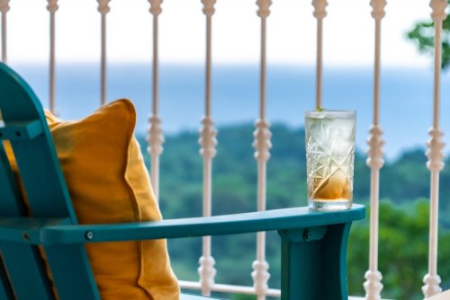 Glass of a refreshing drink on a balcony with ocean and forest views at Roça Sundy