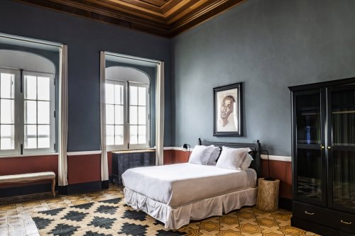 Quarto espaçoso com grandes janelas e design vintage no Roça Sundy Boutique Hotel.