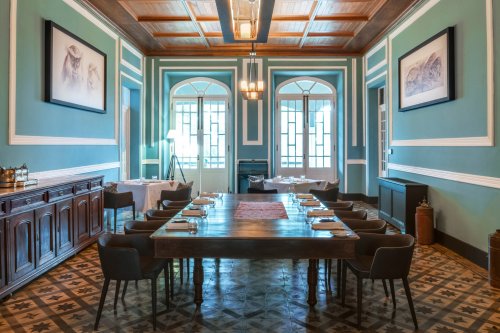 Elegant dining area at Roça Sundy with a long wooden table, art on the walls, and large windows