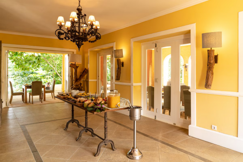 Pequeno-almoço buffet na sala de jantar amarela do Belo Monte, candelabro aceso e portas abertas para os jardins.