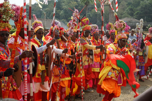 Carnival parade on Príncipe, performers in bright traditional costumes with flags, sticks and drums.