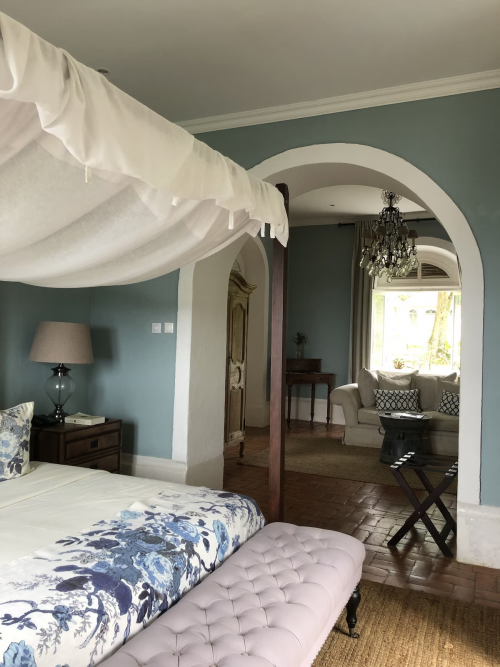 Panoramic Suite interior at Belo Monte, canopy bed and arched doorway leading to a separate lounge with chandelier.