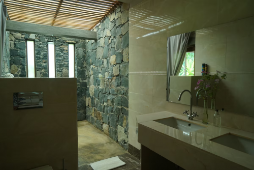 Panoramic Suite bathroom with stone walk-in shower, slatted roof light and double vanity facing a garden window.