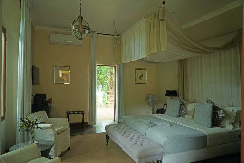 Spacious suite at Belo Monte with canopy bed, seating area and doors opening to a terrace among the trees.