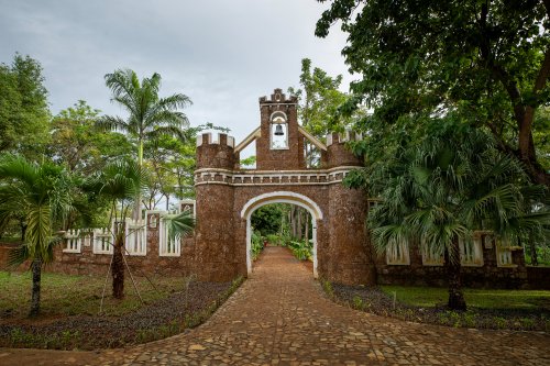 Portão fortificado em pedra e campanário ladeados por palmeiras e jardins tropicais no Belo Monte