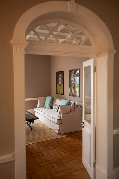View through an arched doorway into the Belo Monte lounge with a cream sofa and framed portraits