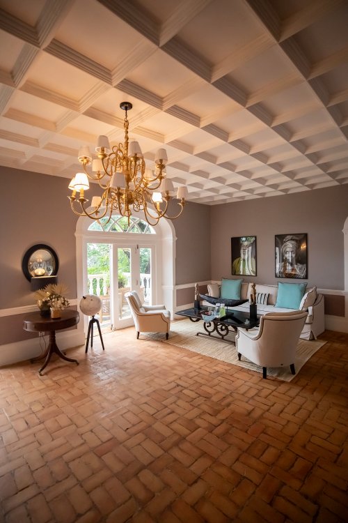 Sala de estar do Belo Monte com teto em caixotões, candelabro dourado e pavimento de tijolo de terracota com acesso ao terraço