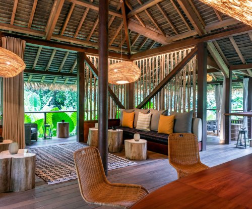 Covered terrace with seating, small wooden tables, and large hanging lamps at Sundy Praia