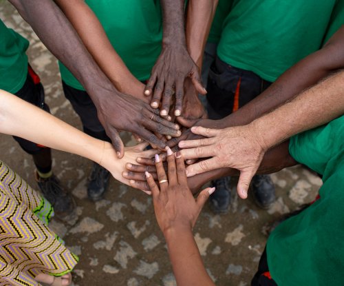 Circle of hands with different skin tones touching in the centre on Príncipe Island.