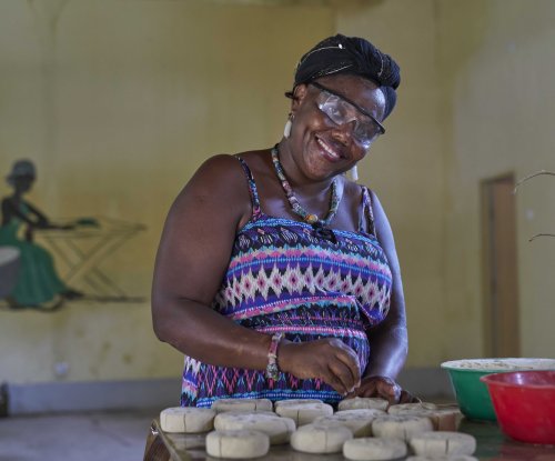 Local worker in a colourful dress and safety goggles smiles at us while working.