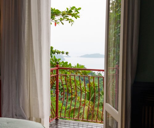 Balcony doors of the Belo Monte Panoramic Suite opening to a rainforest and ocean view
