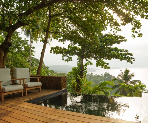 Private plunge pool and deck with armchairs overlooking the rainforest and ocean at Belo Monte