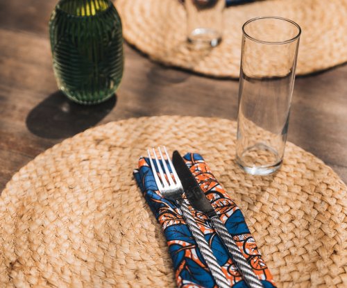 Talheres em guardanapo estampado sobre individual de palha no Bom Bom Beach Club