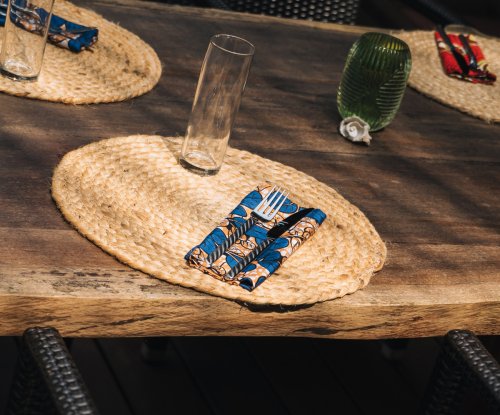 Mesa posta com individuais de palha e guardanapos batik no Bom Bom Beach Club